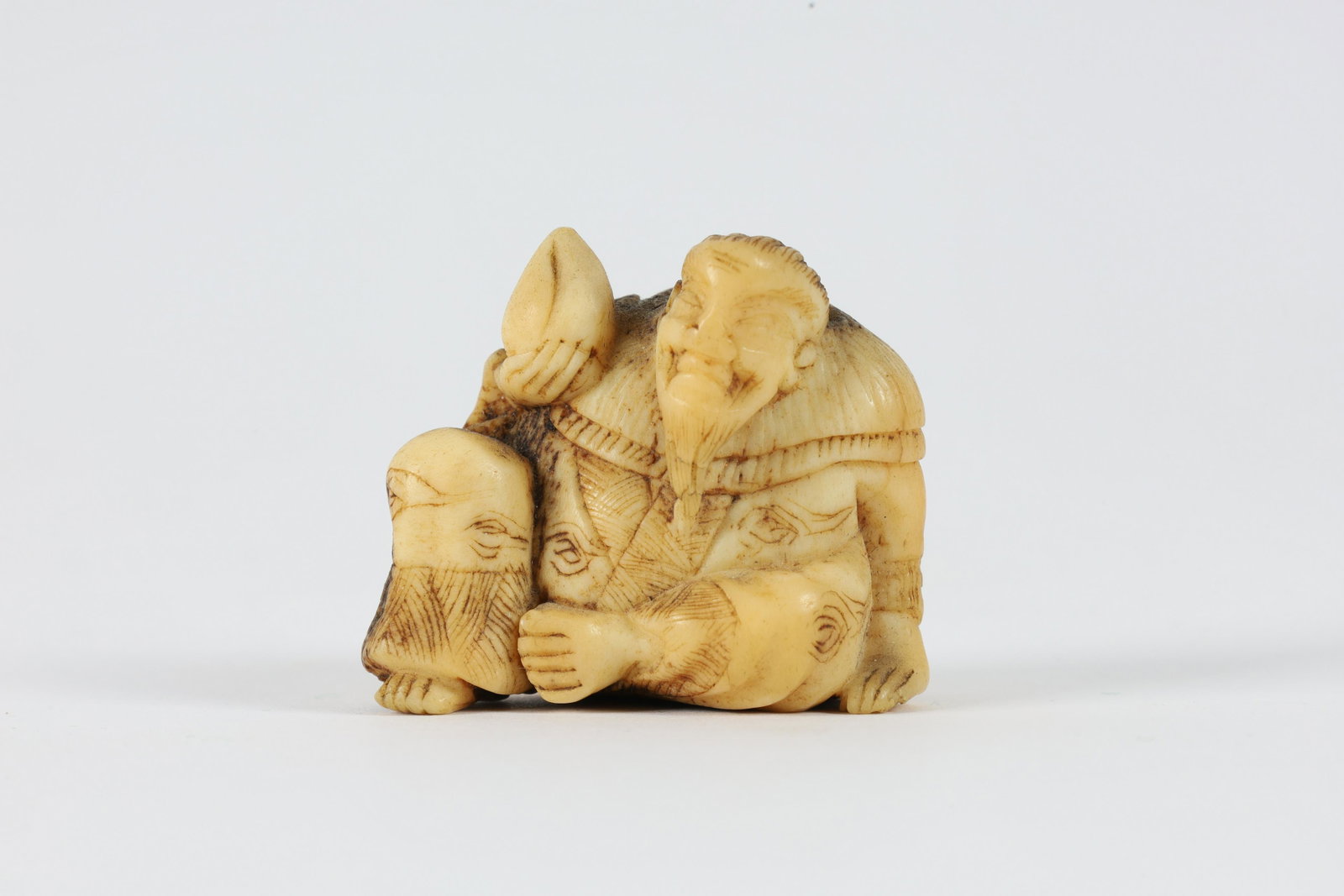 Japanese Carved Bone Netsuke, Seated Man: Japanese Carved Bone Netsuke, Seated Man Holding Peach. Circular area missing from back of head. Measures 1.5 inches L x 1.25 H x 1 W.