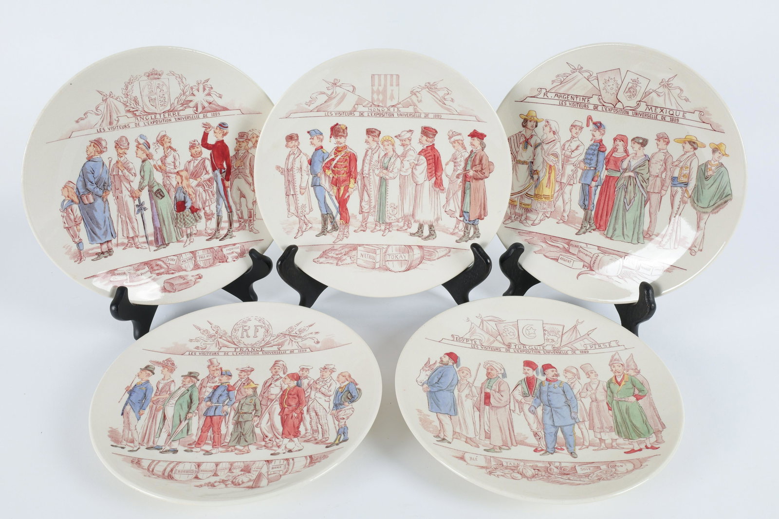 Sarreguemines Universal Expo Souvenir 1889 Plates: Set of five French cream coloured pottery souvenir plates by Sarreguemines manufactured for the L'Exposition Universelle held in 1889, each plates is unique and hand colored and shows the country cres