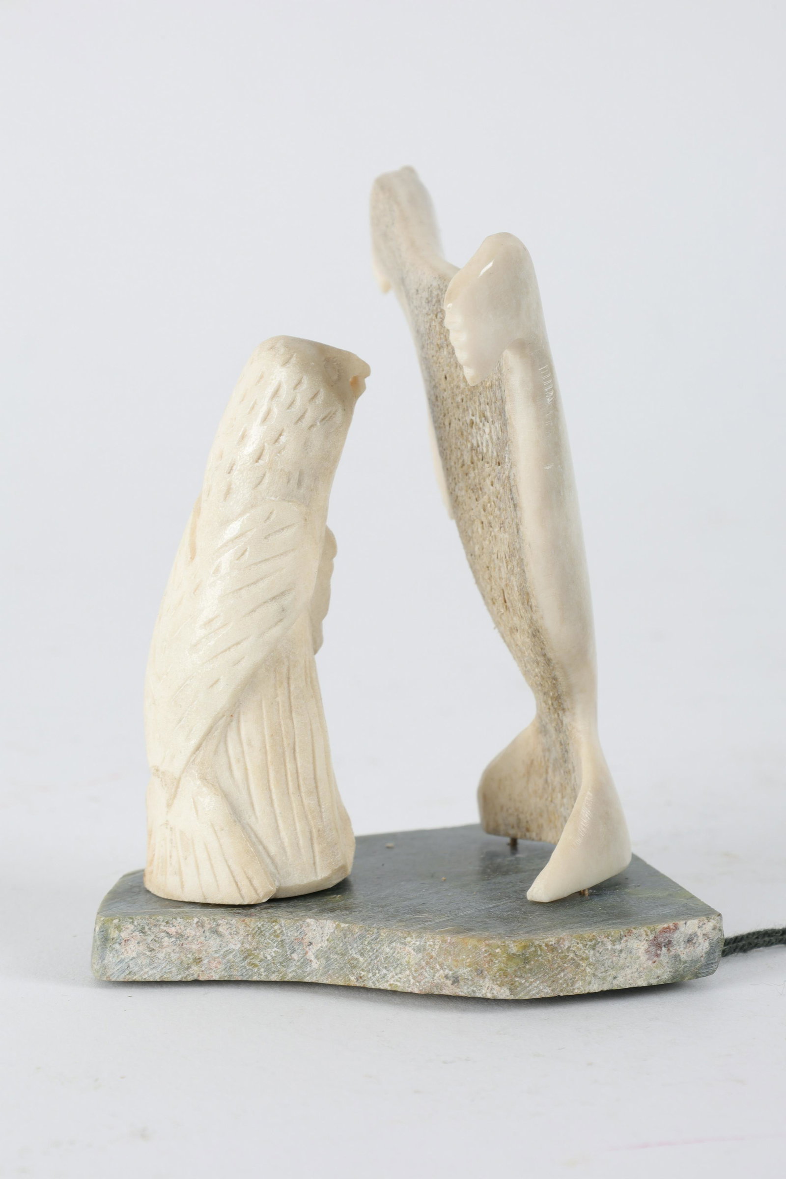 Inuit Carved Bone Sculpture Mapie Kakkik: Inuit Carved Bone Sculpture Mapie Kakkik on Soapstone base. Carved seal with eagle on face. Measures 2.5 x 2 x 4 inches H. With original certification tag.