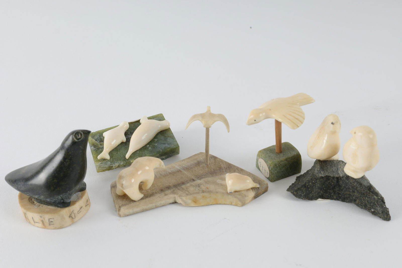 Lot Carved Inuit Small Figures, Birds, Bear, Seals: Lot of Small Carved Eskimo Inuit Figures, Birds, Bear, Seals. Mounted on bone and stone. Stone bird on bone base signed Alie, Syllabics, measures 2 inches H x 2.5 L x 1.25 W. Set of two seals on stone