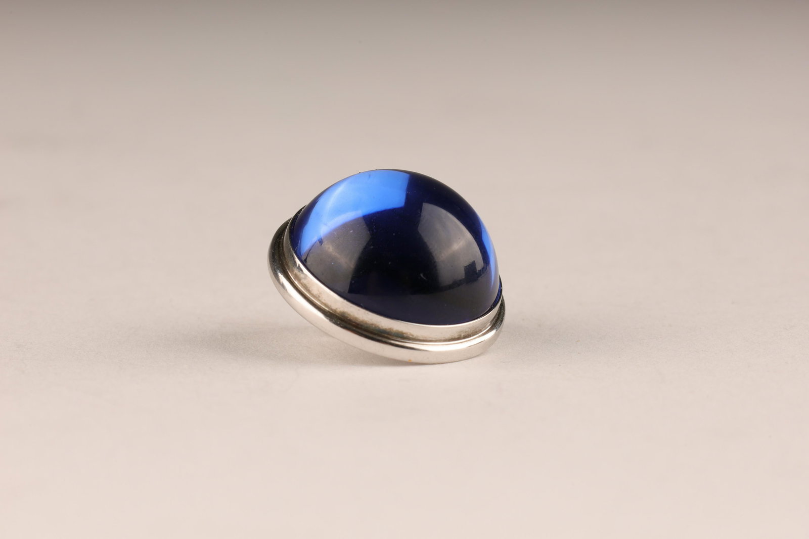 Lalique Blue Glass Cabochon Lapel Pin: Lalique Blue Glass Cabochon Lapel Pin. Marked on verso Lalique France. Measures 1 inch diameter.