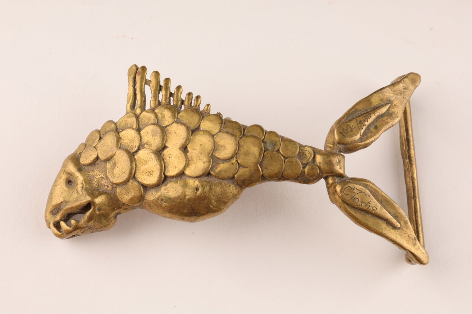 Brutalist Modernist Carl Tasha Piranha Belt Buckle: Brutalist Modernist Carl Tasha (1943-2006) Brass Piranha Belt Buckle, Signed in two places and numbered, 102/200. 3.5 inches L x 2 H.
