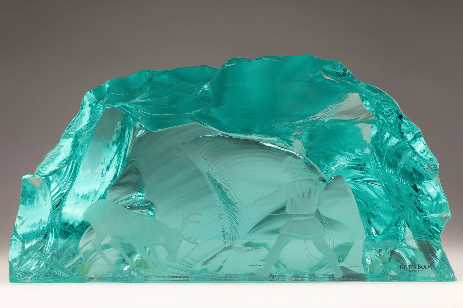 Vicke Lindstrand Kosta Boda Art Glass Sculpture: Vicke Lindstrand for Kosta Boda Aqua Blue Art Glass Sculpture with Figure Pulling a Caribou / Reindeer. Signed on base, Marked and Numbered. 5.25 inches h x 10 w x 4.5 d.