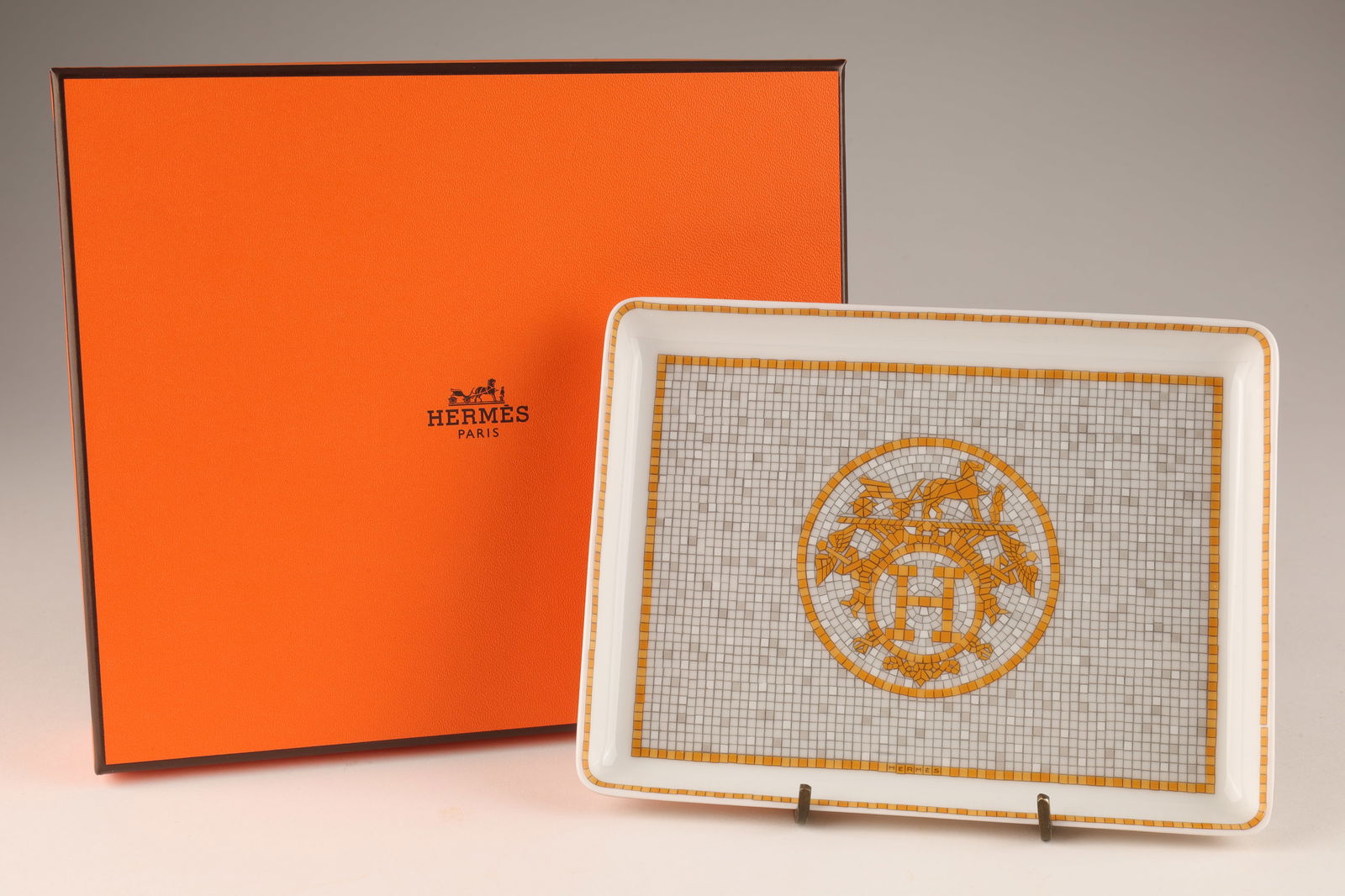 Hermes Porcelain Mosaique Au 24 Or Small Plate: Hermes Porcelain Mosaique Au 24 Or Sushi / Small Plate. New in box, made in France. Plate measures 4.75 inches x 6.25 L, box measures 6.5 x 7.5 x 1.75 inches H. With its geometric pattern, the Mosaiqu