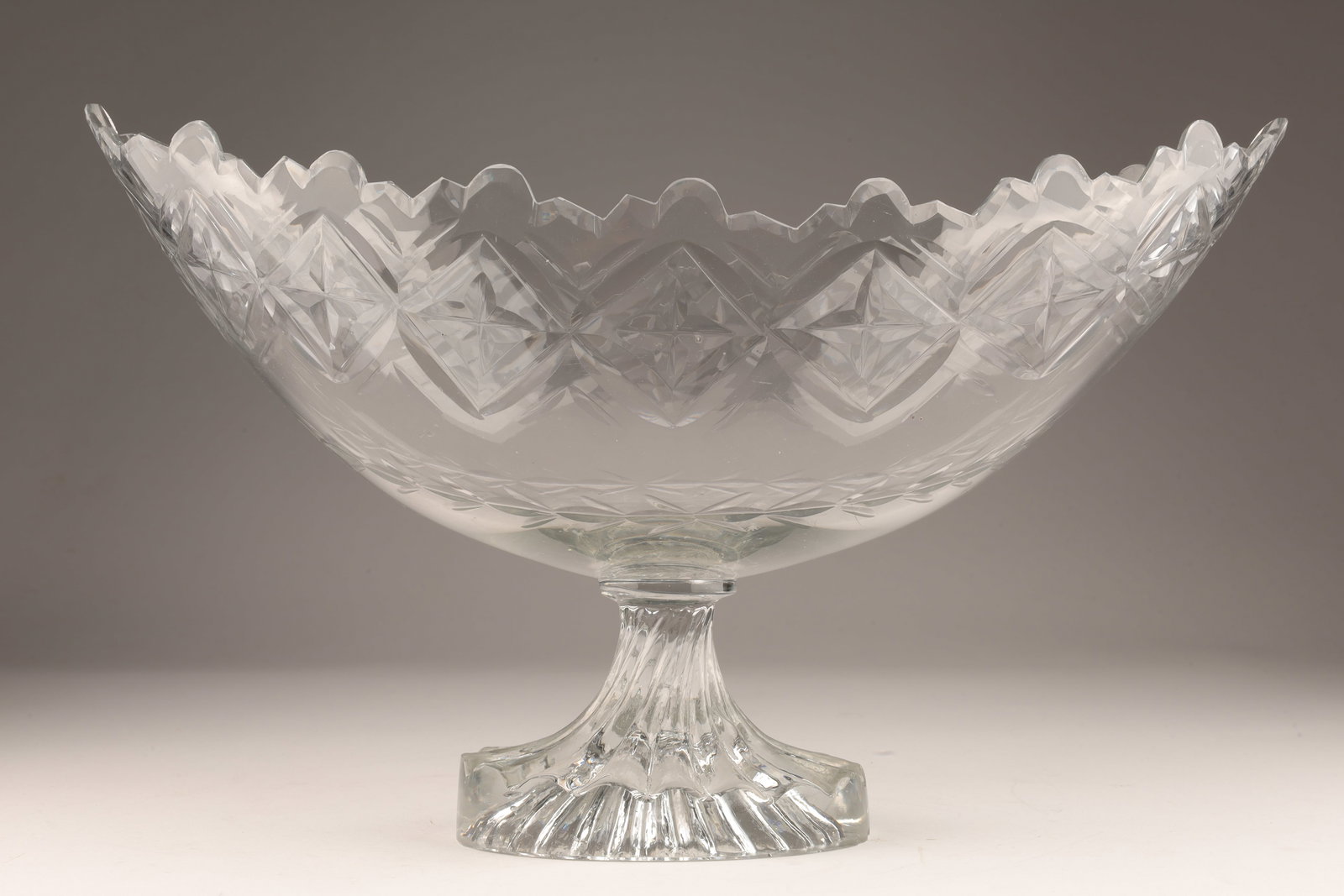 Anglo Irish Georgian Cut Glass Boat Shaped Bowl: Anglo Irish Georgian cut glass boat shaped bowl with Van Dyke rim set on molded lemon squeezer oval foot, circa 1790; Condition statement chip to bottom edge of foot. 14 inches L x 6 W x 8.5 H.