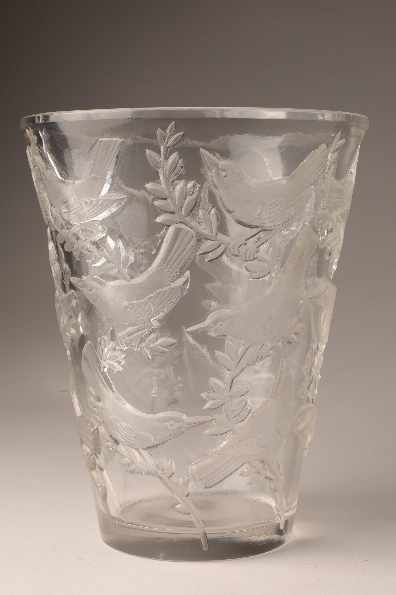 R. Lalique Art Glass Grives Vase, Birds: Rene Lalique Art Glass Grives Vase. Press molded clear glass with an all-over decoration of small birds in various poses. Etched R. Lalique France on base. Small fleabite to rim. 7 inches H x 5.75 W.