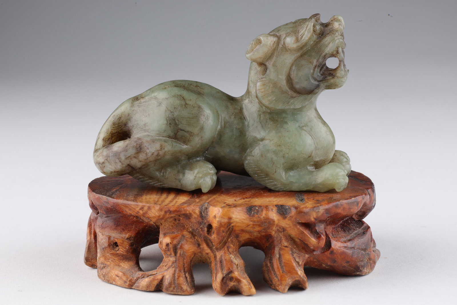 Chinese Carved Green Jade Stone Beast: Chinese Carved Green Jade Stone Beast / Dragon Dog on carved wood stand. Beast measures 3 inches L x 2 H, stand measures 1 inch H.