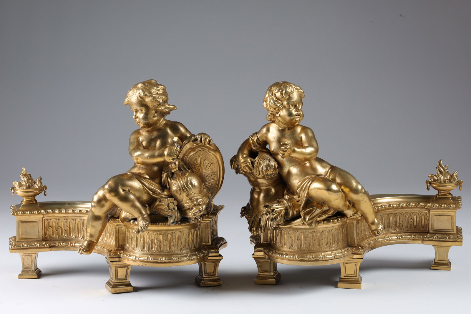 Pair Large 19th C French Gilt Bronze Chenets: Pair of Large 19th C French Gilt Bronze Chenets, decorated with putti, helmets and armour. 18 inches L x 15 H x 8 deep.