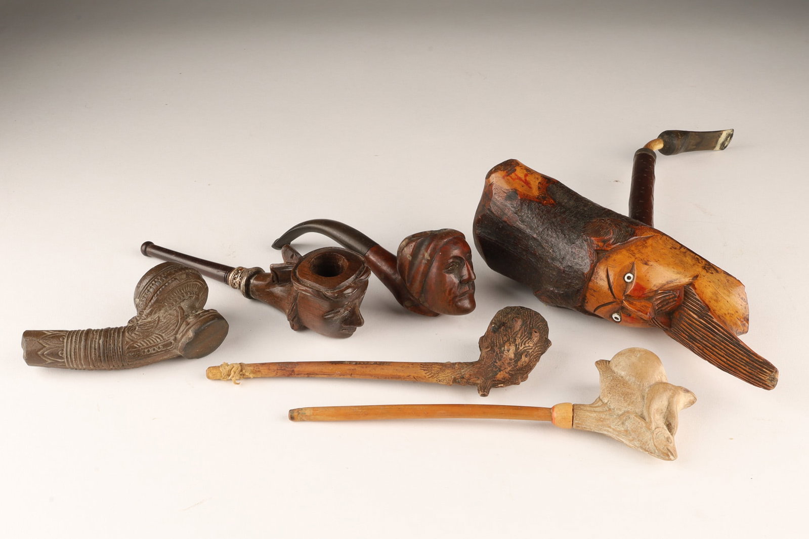Lot of Antique Figural Smoking Pipes: Lot of 6 Antique Figural Smoking Pipes, carved wood, clay pipes, Scotland briar carved pipe measures 6.5 inches L. Large face pipe measures 7.5 inches L.