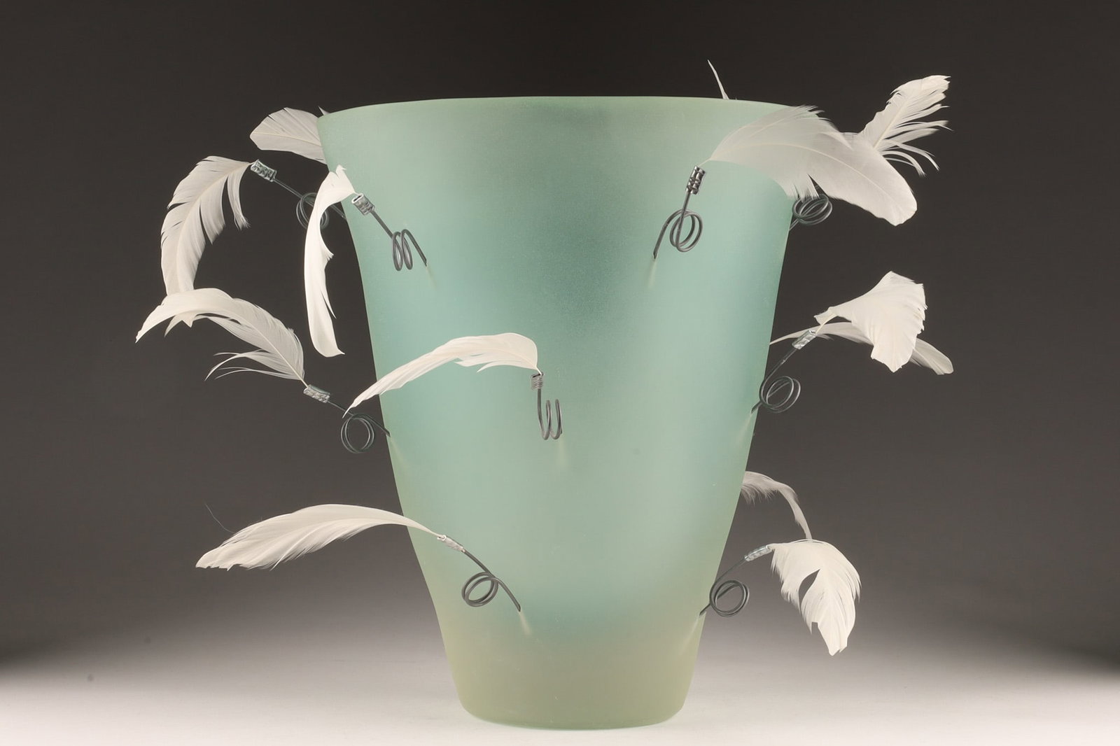 Artecnica Los Angeles Feather Polymer Vase: Unique pale green polymer vase with attached feathers around the sides, with original company label on base, by Artecnica of Los Angeles. Some feathers bent, please see photos. 10 inches H x 8.5 W x 7