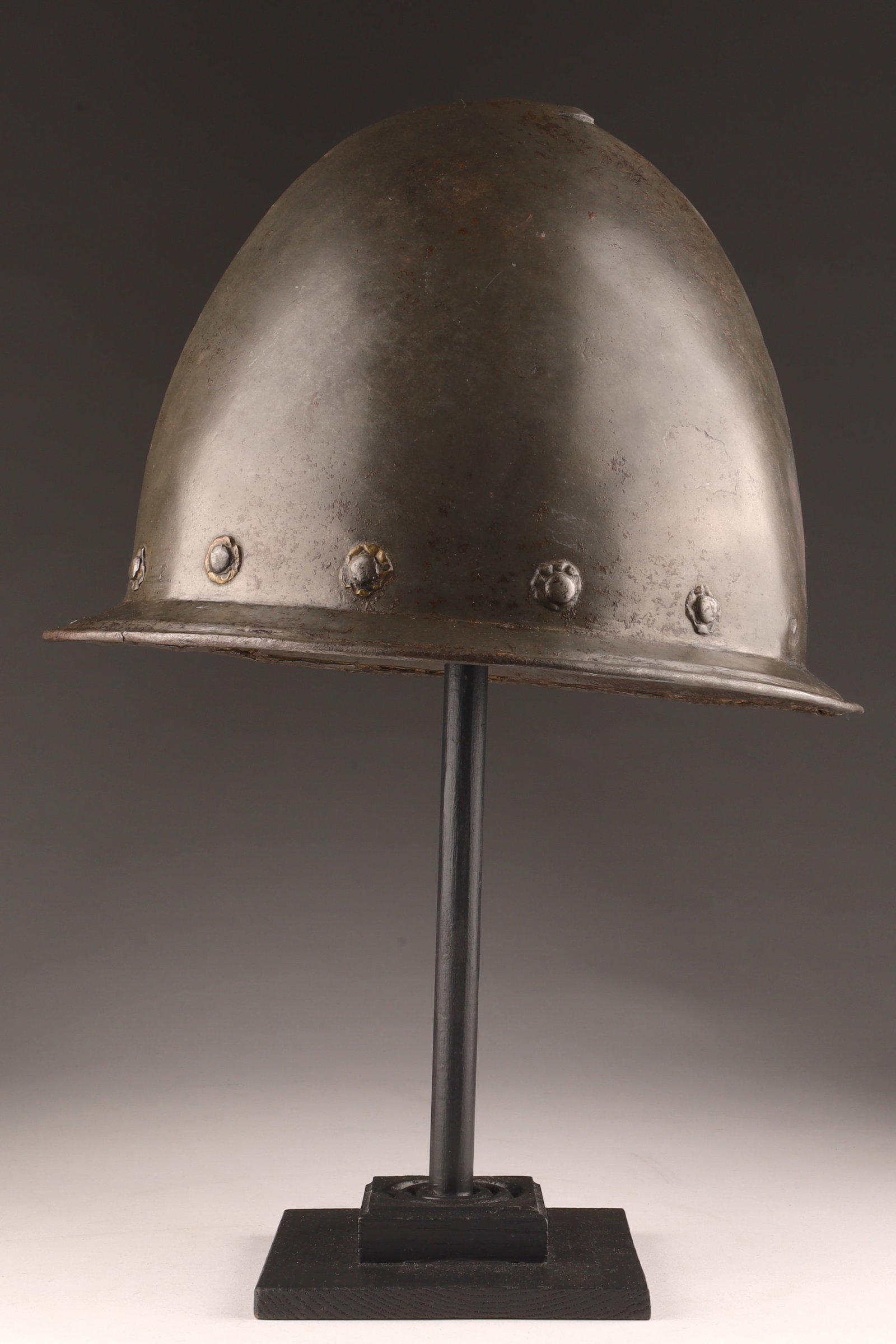 Antique Portuguese or Spanish Iron Cabasset Helmet: Antique Portuguese or Spanish Iron Cabasset Helmet, with rolled brim and pointed comb decorated with floral rivets along the brim. Some loss, damage to brim, missing a few flowers. 11 inches L x 8.5 H
