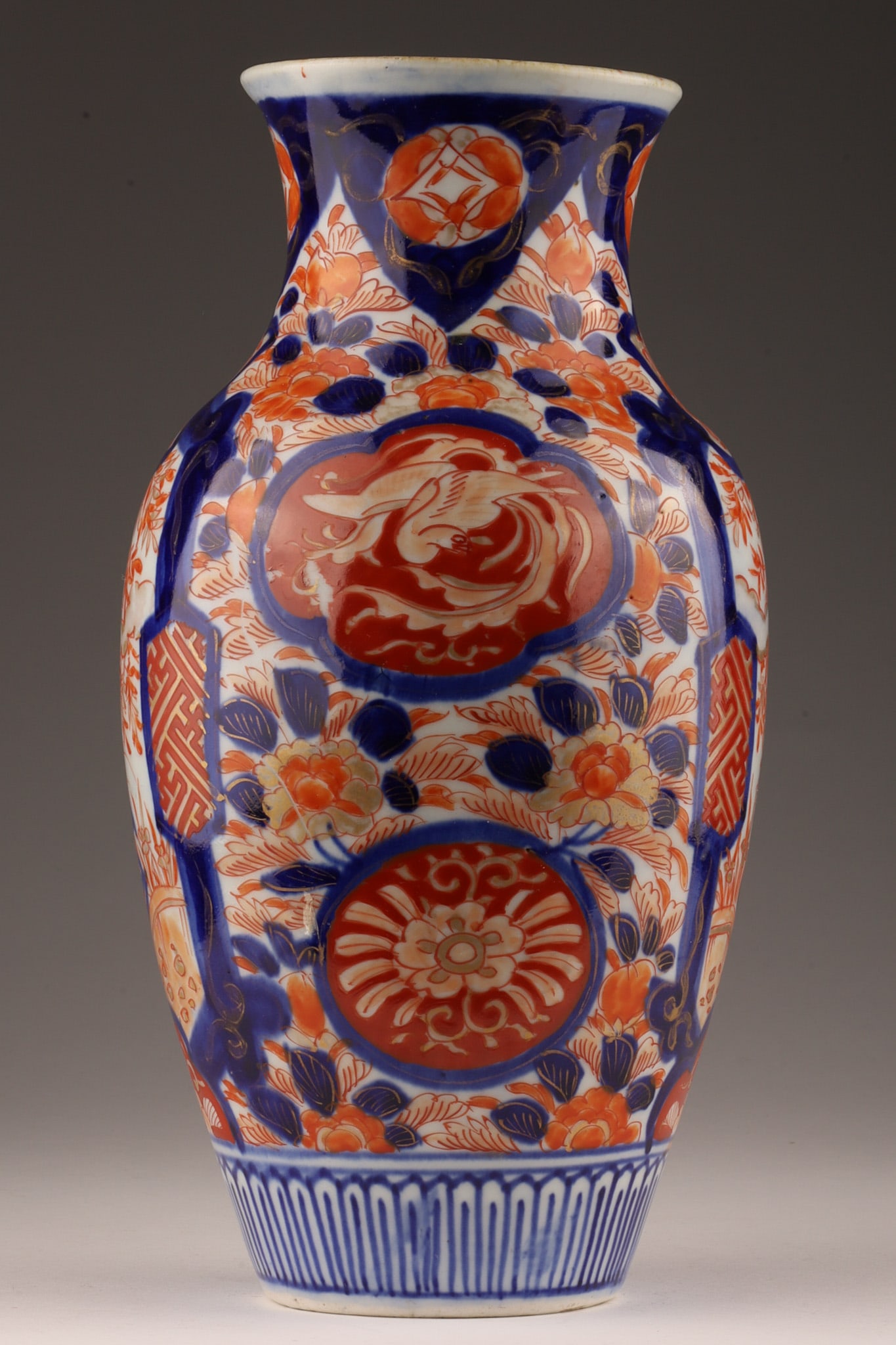 Japanese Meiji Period Baluster Imari Vase: Japanese white porcelain baluster shaped vase with hand painted Imari designs in burnt orange and cobalt blue with red cartouche showing phoenix, circa Meiji period 19th century. Signed on base, marke