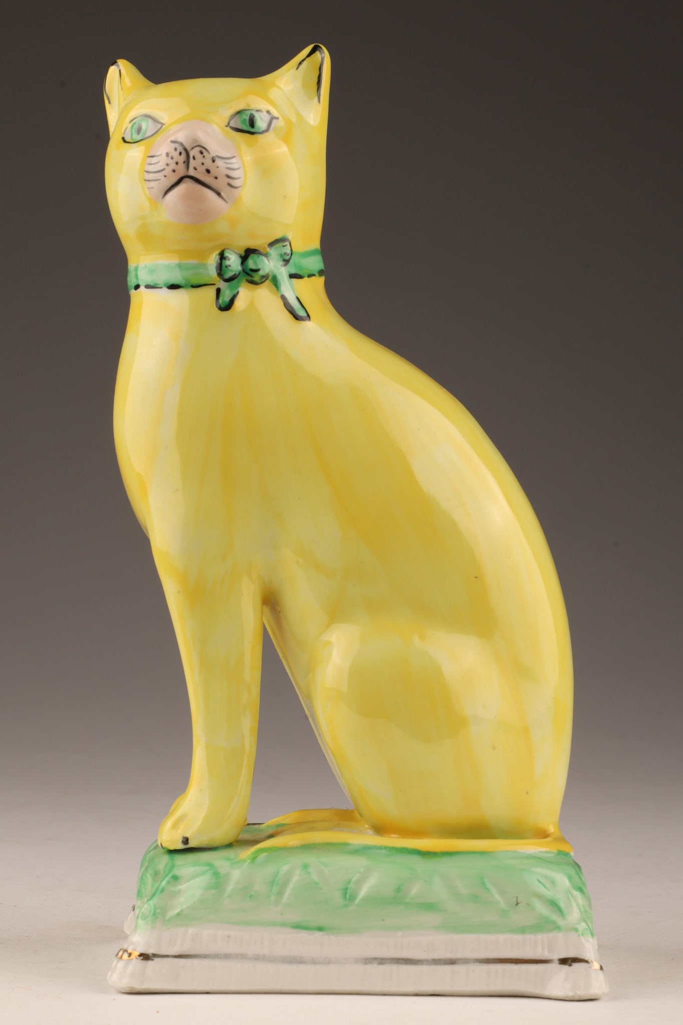 19th C Antique Yellow Staffordshire Porcelain Cat: 19th C Antique Yellow Staffordshire Porcelain Cat sitting on a green pillow with gold banding. 7 inches H x 3.5 W x 3 deep.