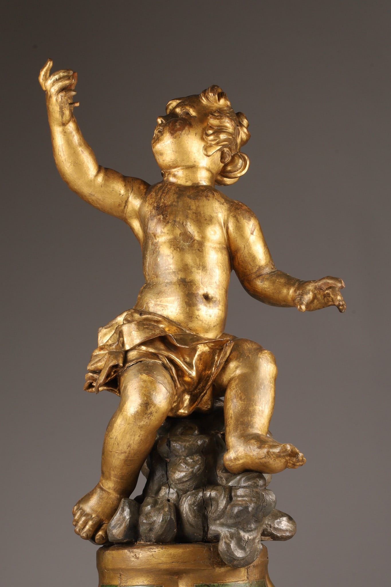 Large 18th C Italian Antique Carved Giltwood Putti: Large Italian 18th C Carved Giltwood Figure of a Putti Gesturing upward with one arm outstretched, carved drapery covering its lower body. Seated upon a polychrome Trompe L'Oeil painted pedestal base.