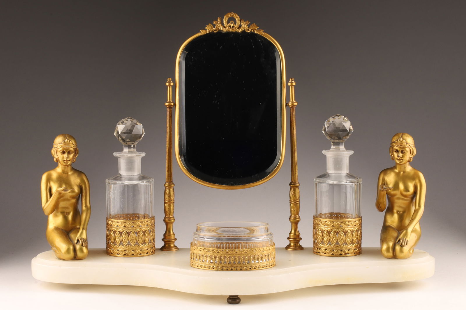 1930s Art Deco German Nude Lady Dressing Vanity: 1930s Art Deco German Gilt, Marble and Nude Lady Figures Dressing Table Vanity with two faceted scent bottles and one jar, beveled mirror on pivoting stand. 10.5 inches H x 14.5 W x 6 deep.