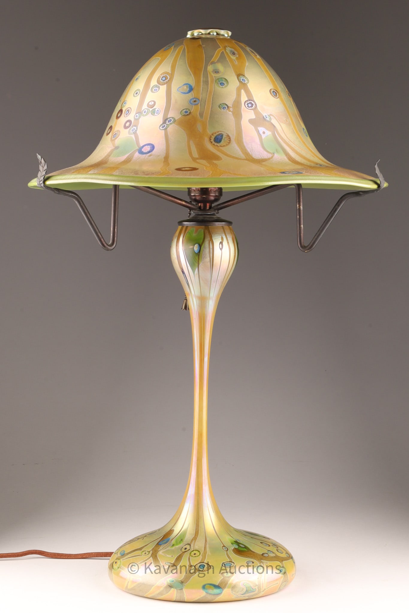 Phoenix Studios John Cook Millefiori Glass Lamp: Phoenix Studios John Cook art glass table lamp. Features iridescent green circular flared shade and body with a green, blue and brown millefiori pattern on a closed base. Etched mark John Cook Phoenix