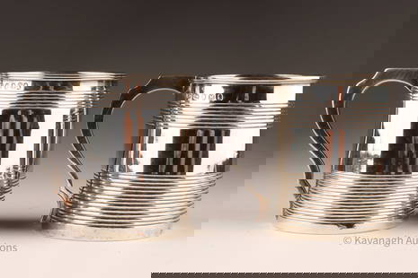 Pair Georgian Sterling Silver Beer Cider Steins: Pair of Georgian English sterling silver diminutive beer cider steins, both with a horizontal reeded design and one with an heraldic symbol and monogram, one showing hallmarks for London 1807, maker E