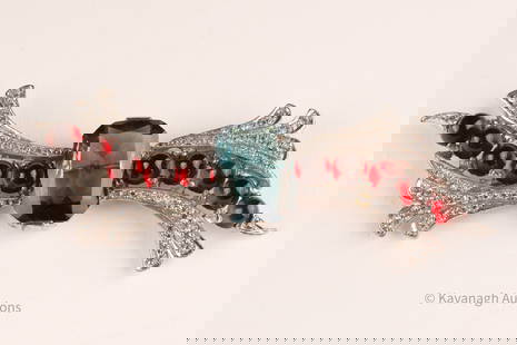 Art Deco Sterling Silver and Rhinestone Brooch: A Sterling silver (marked) brooch, of art deco style, set with synthetic white stones in pavé style. Also set with cabochon cut red stones and one central blue, cut-corner rectangular stone. Stones n