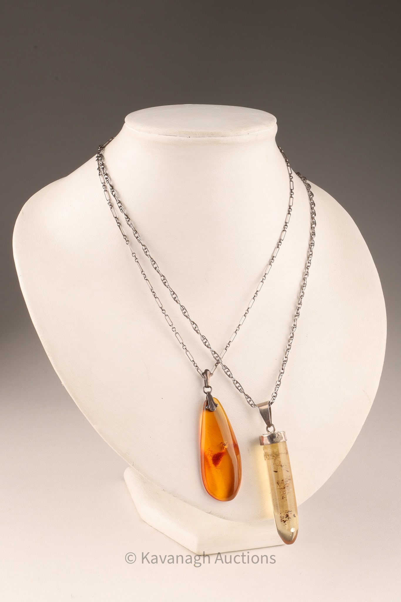 A Pair of Amber Sterling Silver Pendant Necklaces: A pendant of amber from Chiapas (52mm in length) mounted on sterling silver marked “Mexico”. Presented on a 20 inch assorted chain. A second amber pendant on sterling silver measuring 52mm in 