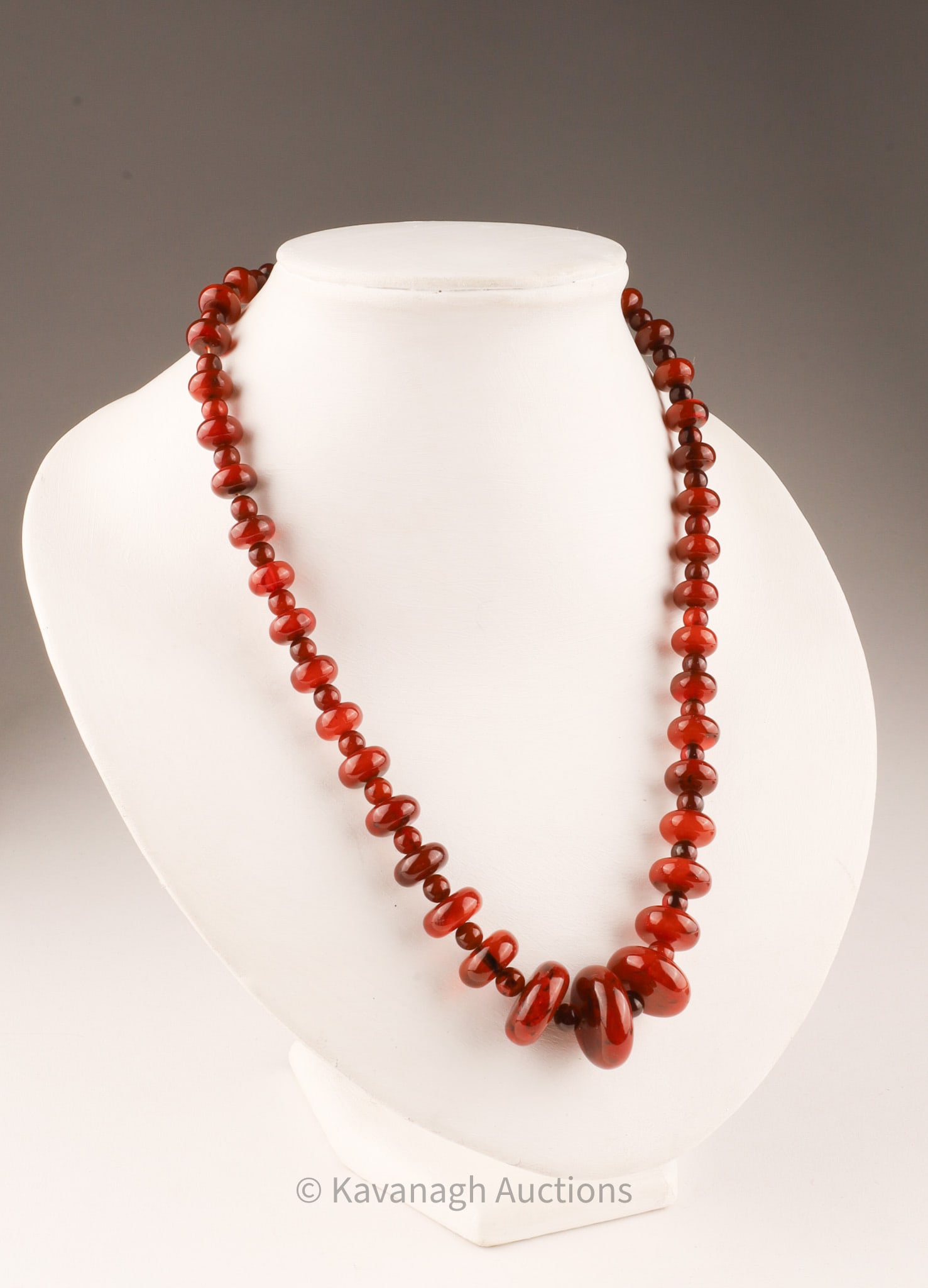 Polished Amber bead necklace: A polished disc and graduated bead amber necklace. Silvered metal lobster clasp.The largest measuring 21 x 8.3mm. Total length is 17 inches.
