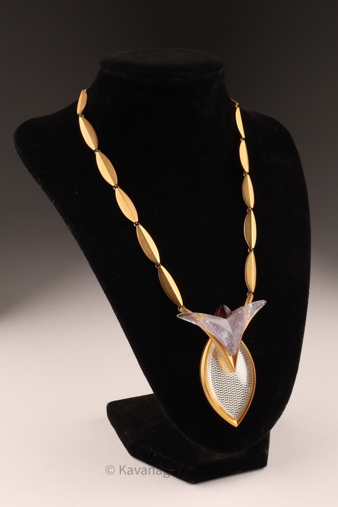 Linda MacNeil Art Glass Floral Series Necklace: Rare gold toned necklace from the Floral series by designer American glass artist Linda MacNeil (1954 - ), the triangular pendant with quartz and engraved crystal design from a lobed gold tone linked