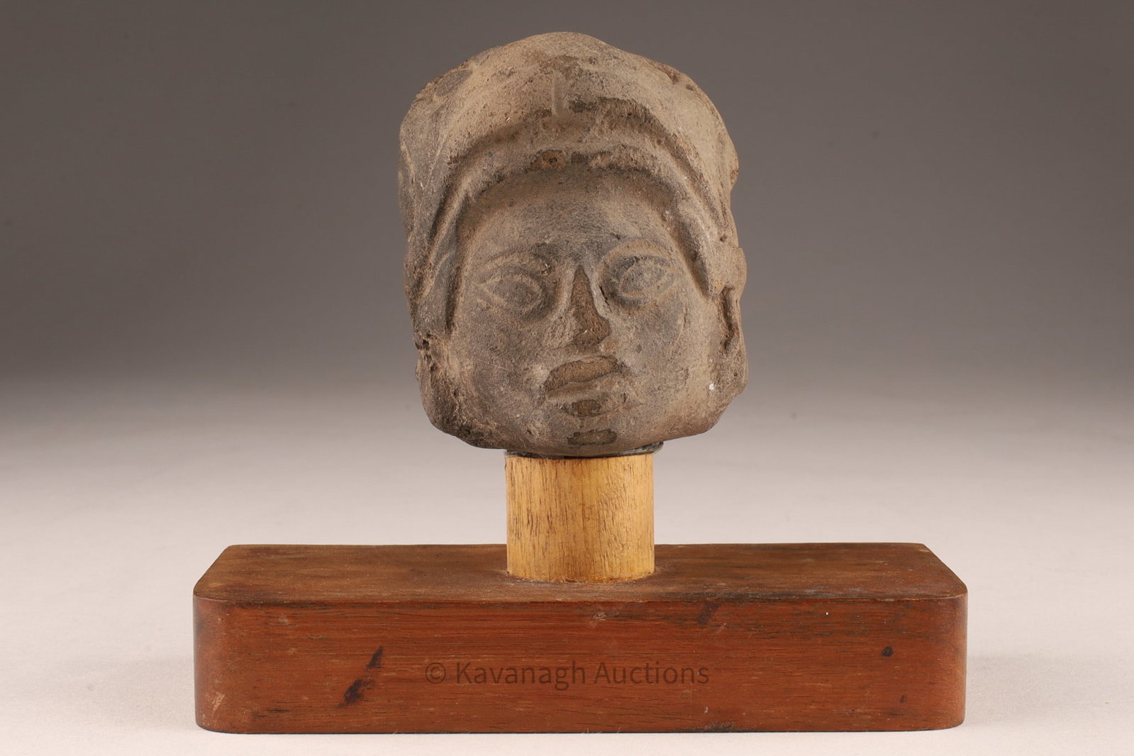 Pre-Colombian Toltec Sculpture Bust of Quetzalcoatl: Toltec terracotta sculptural head depicting Quetzalcoatl, the feathered serpent deity of Mesoamerican mythology. The piece is mounted on a wooden base and accompanied by an archaeological label indica