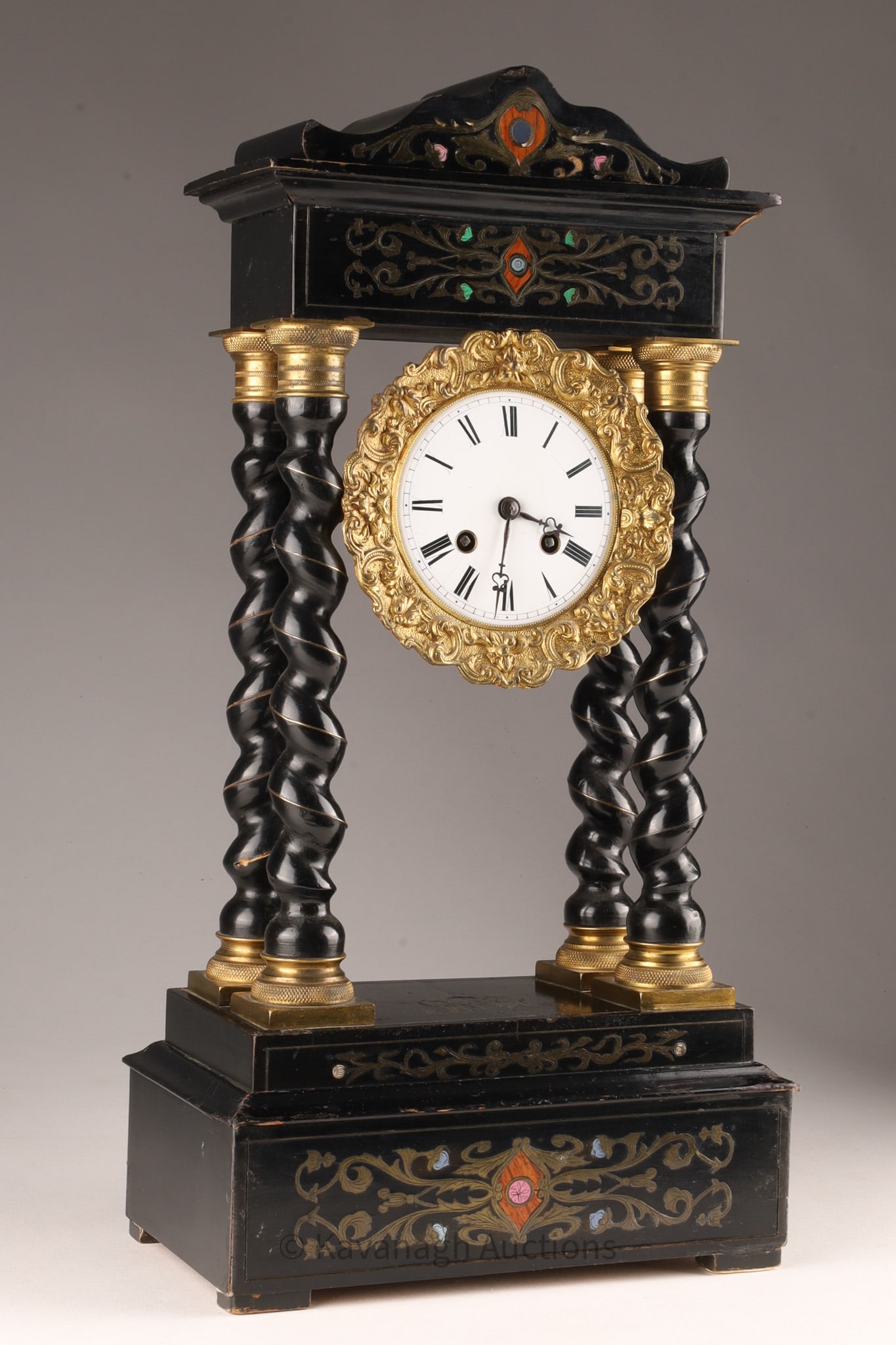 19th c. Ebonized Inlaid Portico Clock: Inlaid with brass and hardwood and enameled decoration. Some scuffs and loss to brass on one barley twist column.. 19.5 inches H x 10 W x 5.5 deep. Loss to brass on barley twist column, knicks and scu