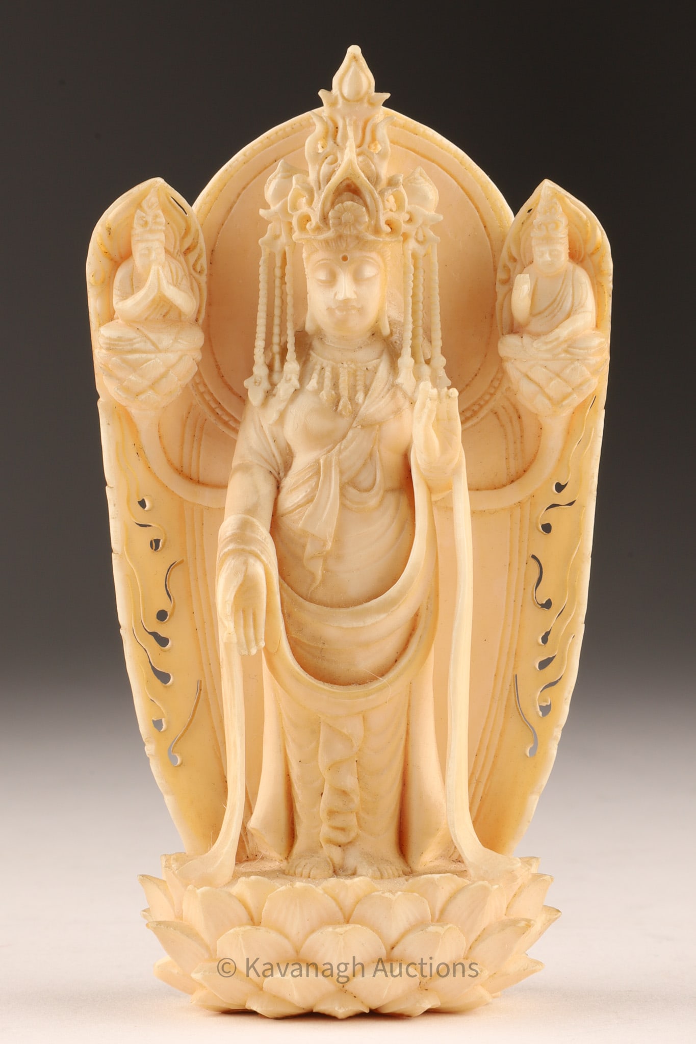 Chinese Carved Figure of Guanyin with Attendants on Lotus Base: A finely carved representation of Guanyin, the bodhisattva of compassion and mercy, standing gracefully atop a fully open lotus pedestal, symbolizing purity and transcendence. The central figure is ri
