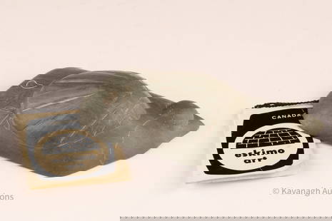 Inuit Soapstone sculpture Jimmy Kattuk Belcher Islands: A compact stylized carved object in green serpentine with lightly incised details. Accompanied by its original Canadian Eskimo Art igloo tag and government disc number label (E9-2515), identifying