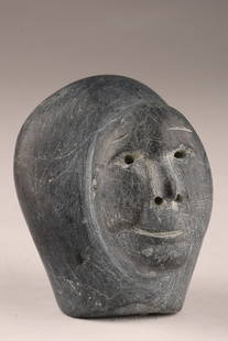 Inuit Soapstone sculpture of a portrait / Stone Carving Human Head: A small Inuit carving of a human head in dark stone, with incised mouth and drilled eye/nose details. The compact form and simplified features are characteristic of mid-20th century Inuit