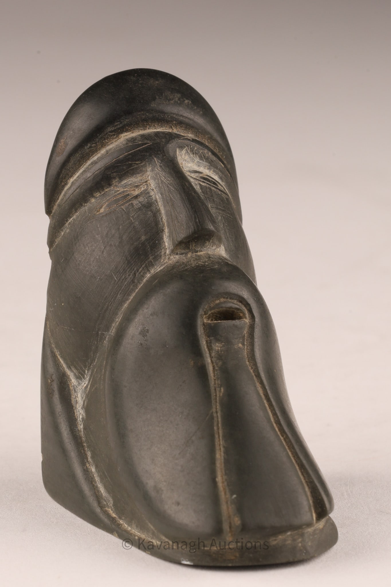 Samson Meeko (E9-32, Belcher Islands) Serpentine Carving, Bearded Head: A finely carved Inuit head in dark serpentine, with stylized beard, deeply incised eyes, and a cap. Signed and labeled to the underside "Belcher Islands / S. Meeko / E9-32", confirming the artist's id