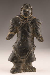 Inuit Soapstone Carving of a Standing Figure in Parka: Carved in dark grey serpentine/soapstone, the figure stands with arms extended; front yoke and hood are crisply incised and a long oval panel at the back suggests an amauti tail (woman's parka).