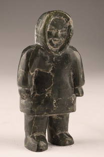 Small Inuit Carving of a Standing Figure: Stone carving, likely soapstone, depicting a standing Inuit figure in traditional parka with hood. The face is simply incised with a faint smile, and the stance is upright with arms at sides.