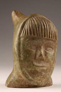 Inuit Soapstone Carving Stylized Head: Northern Canada, mid-20th century hand-carved Inuit soapstone sculpture depicting a stylized human head with prominent bangs and a tapering hooded form. The carving emphasizes the angular planes of