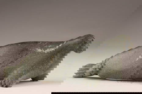 Inuit Stone Carving of a Seal, ca. mid-20th century: Carved in dark green stone, this compact Inuit sculpture depicts a seal with flipper and facial details rendered in low relief. The streamlined body reflects the animal's natural form, with