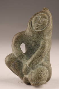 Inuit Soapstone Carving of a Seated Figure, by Muna Parr, Cape Dorset: Carved from mottled grey-green soapstone, this compact figure depicts a seated Inuit person with hands resting across the knees, framed within a deeply hooded parka. The carving has a strong stylized