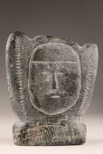 Inuit Stone Carving Stylized Head, Early Work: A vintage Inuit stone carving depicting a stylized head, measuring approximately 5 inches tall. Carved in a minimalist style, the face is defined by incised lines with framing details around the