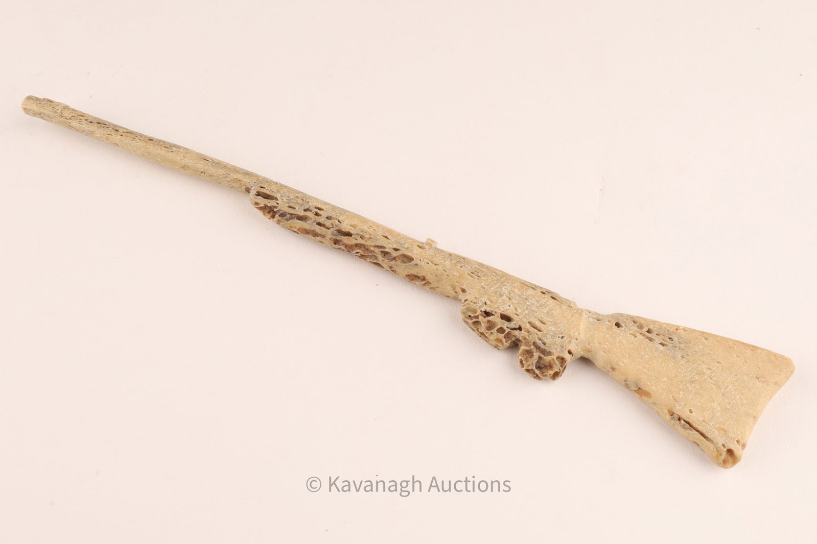 20th Century Inuit Carved Miniature Rifle: A finely hand-carved miniature rifle, fashioned from caribou antler, with well-defined stock, trigger guard, and long barrel. Such carvings reflect the adaptation of traditional Inuit artistry to depi