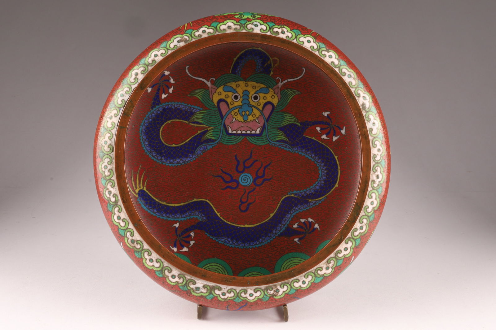 Chinese Cloisonne Dragon Bowl with Mark, 8 inches: A vibrant Chinese cloisonne enamel bowl featuring a coiled five-clawed dragon on a red ground, surrounded by stylized clouds and bordered with ruyi motifs. The underside displays a turquoise enamel fi