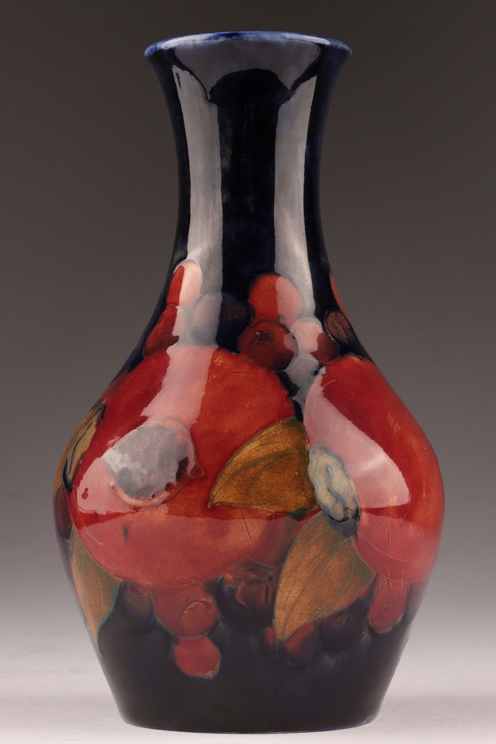 William Moorcroft Graped and Pomegranate pattern Porcelain Vase: A signed Moorcroft Grapes and Pomegrenate Vase measuring 5.75 inches and signed on the base. Makers mark imprint on green wash, with number.