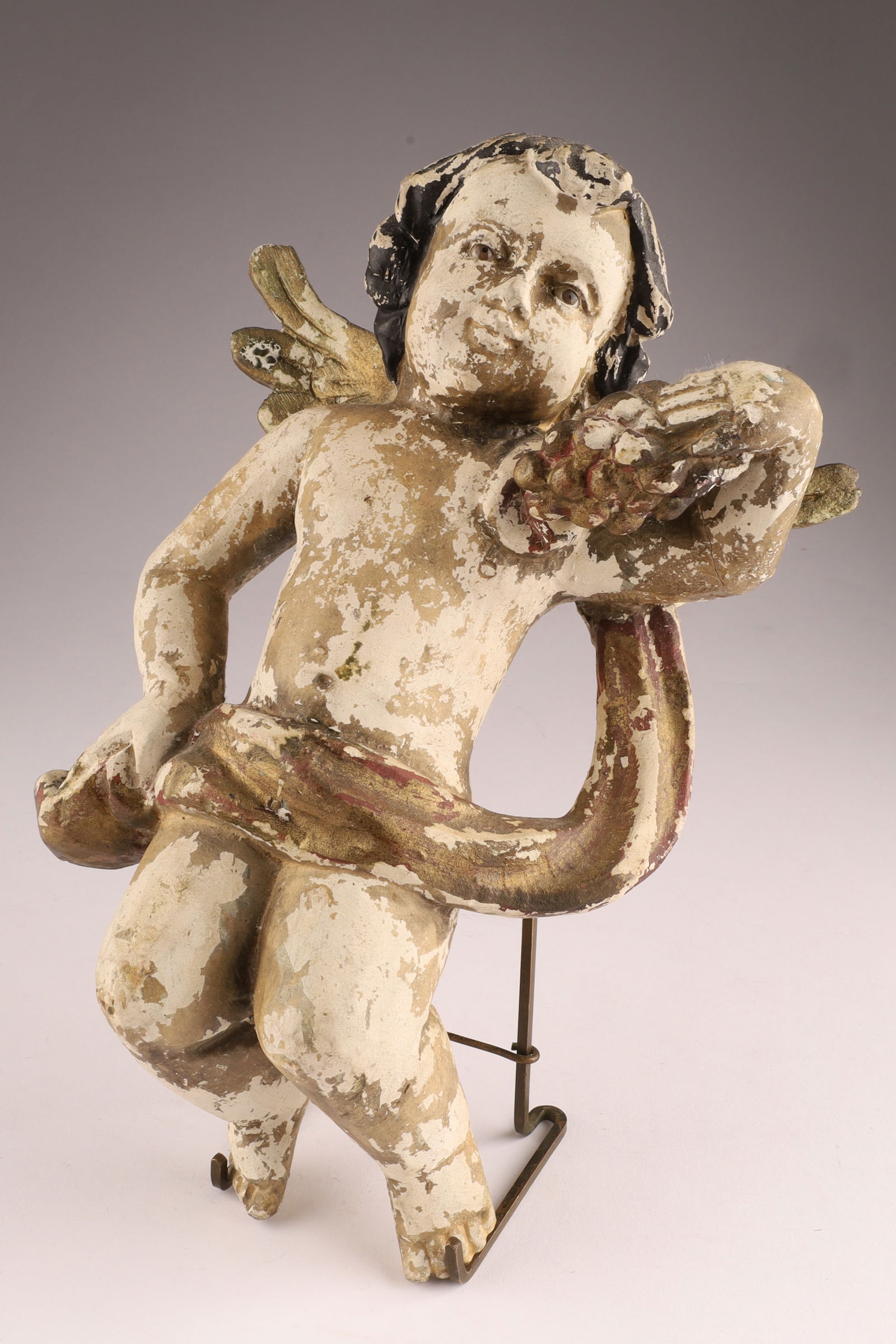 Antique Spanish Santos Wood Hand Carved Polychrome Putti: Antique Spanish Santos Wood Hand Carved Polychrome Putti Cherub holding grapes and garment with glass eyes. Restoration to wings, loss to paint as shown. Measuring 10 inches H x 7 W.