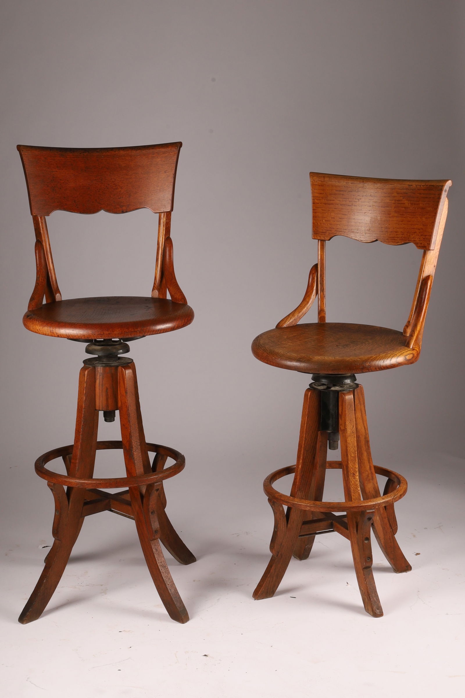 Pair of Industrial Antique Arts and Crafts Oak Swivel Architect Drafting Stools: Pair of Arts and Crafts Industrial Antique Oak Swivel Architect Drafting Stools with Back Rests and Heel Rings, Cast Iron Adjustable Mechanism. Made by the H. Krug Co., Kitchener, Ontario. Measuring 4