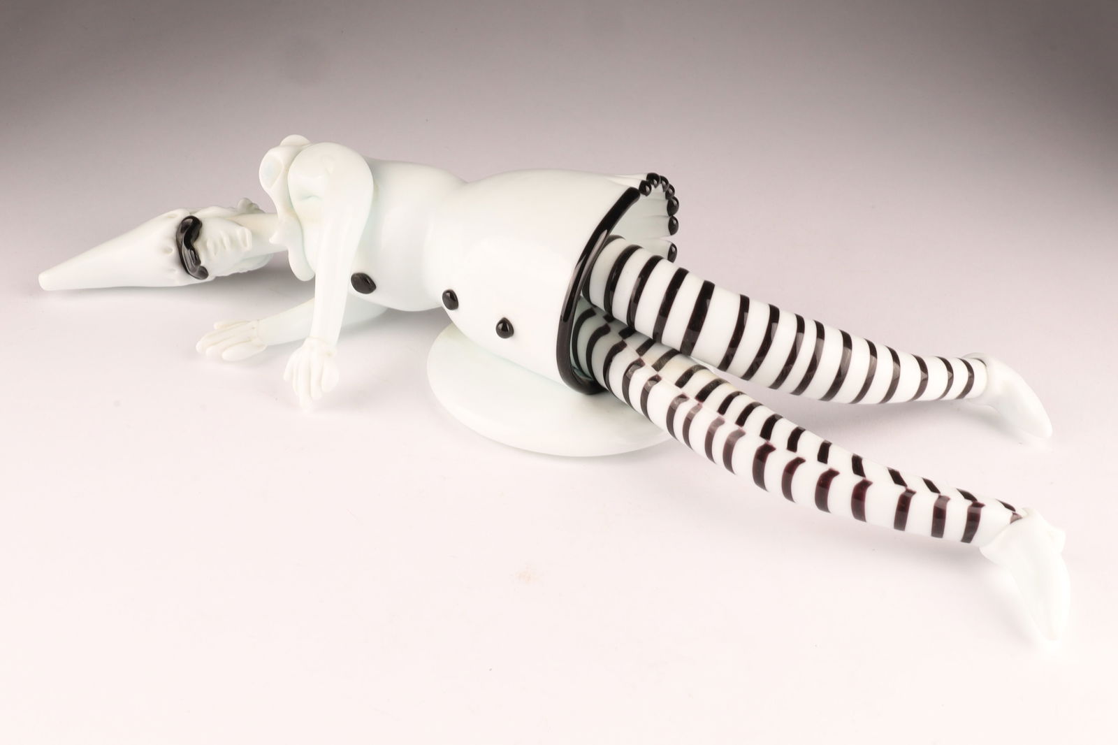 RARE VENINI FULVIO BIANCONI Murano 'Tiepoleschi' Figurine Striped: This scarce Venini ‘Tiepoleschi’ figure, designed by Fulvio Bianconi, depicts a stylized black and white harlequin or clown character lying flat. Measuring 13 inches L x 3 H. From the collection o