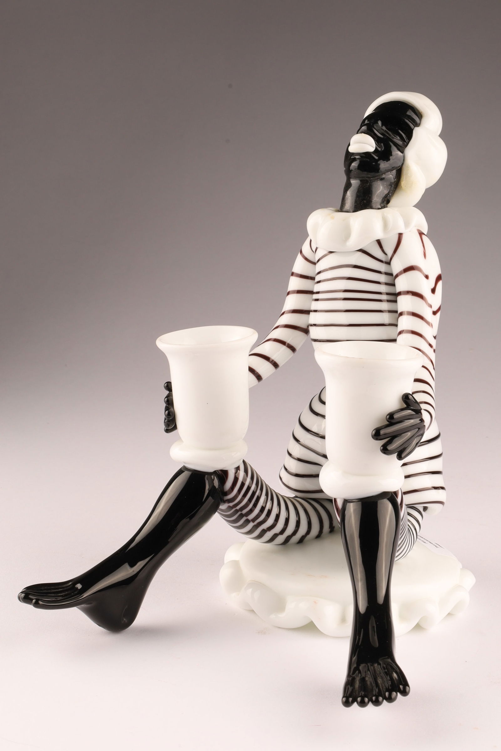 VENINI FULVIO BIANCONI 'Blackamoor' Figural Candlestick: Designed by Fulvio Bianconi for Venini, this ‘Blackamoor’ figural candlestick depicts a stylized seated figure. Measuring 7.5 inches H x 7 W x 6 deep. From the collection of a prominent glass