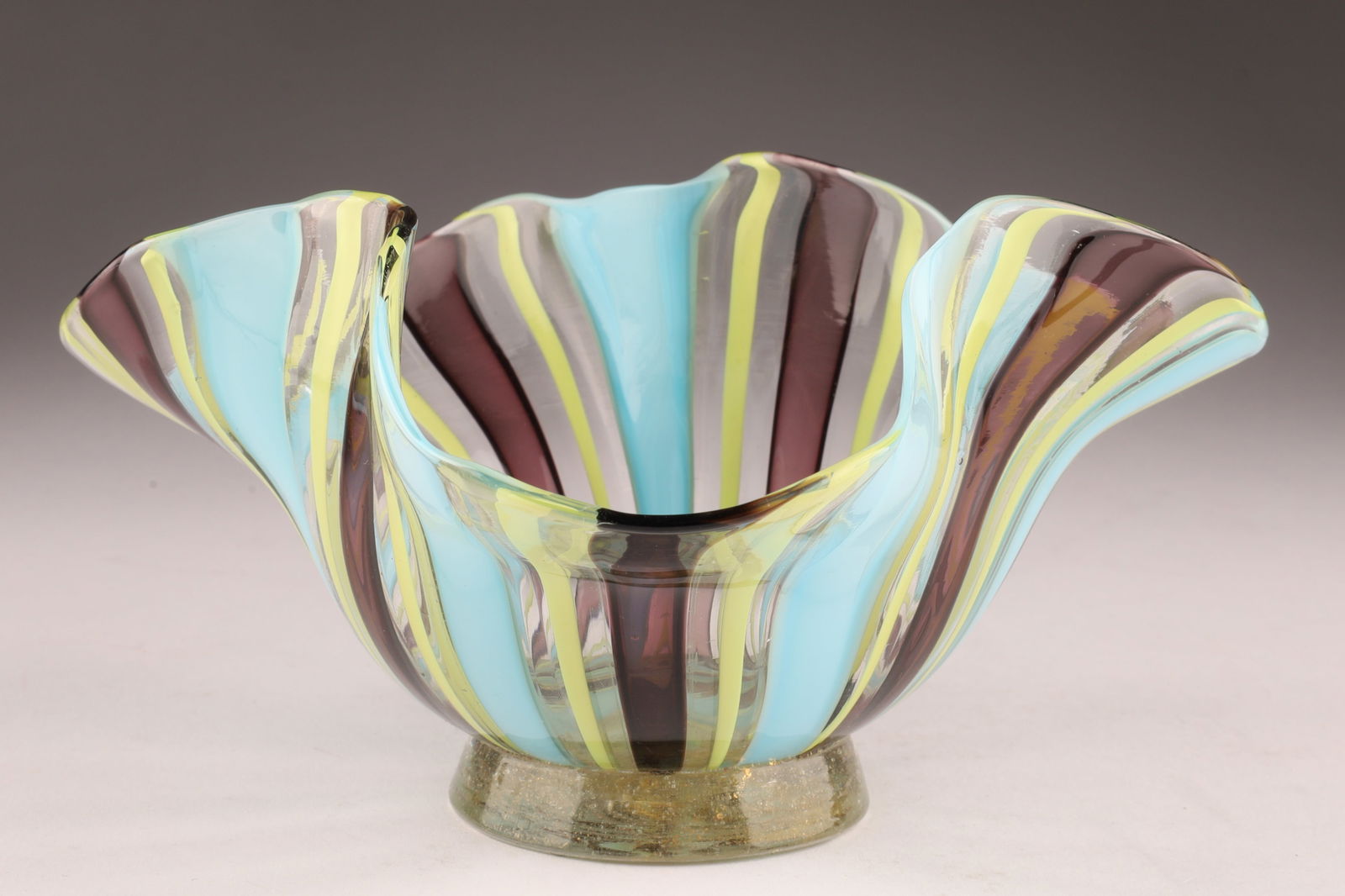DINO MARTENS Attributed Murano Ruffled Ribbon Glass Bowl: Attributed to Dino Martens in the 1950s, this footed ribbon bowl features a ruffled rim and blue, yellow and brown ribbons/stripes, measuring 3 inches H x 6 W. From the collection of a prominent glass