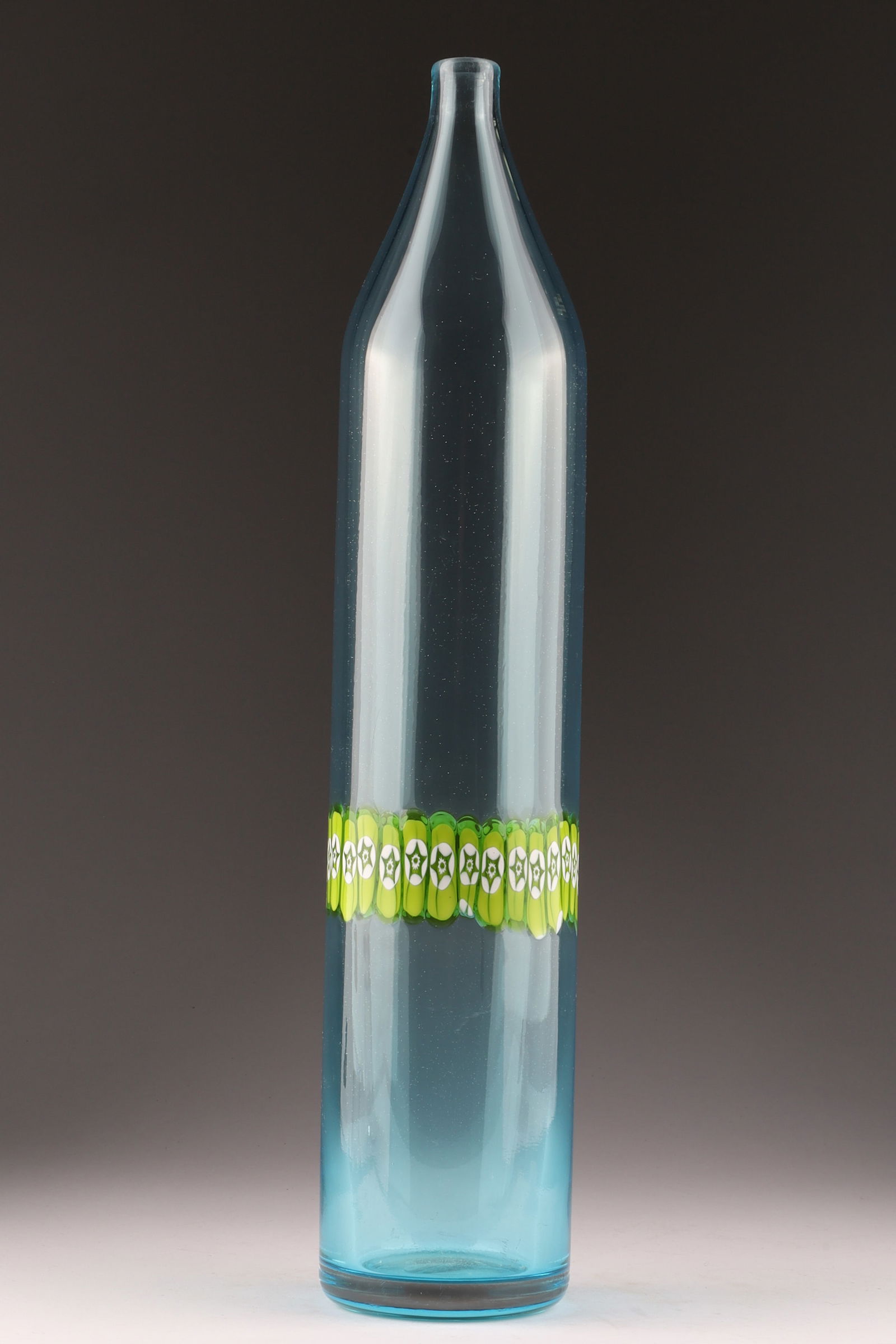 MURANO ART GLASS Murrine Vistosi bottle vase by Peter Pelzel 1962: A murrine Vistosi bottle vase designed by Peter Pelzel in 1962, featuring embedded green and white murrines within a blue glass bottle vase. Heat fracture from production. Measuring 16.5 inches H.