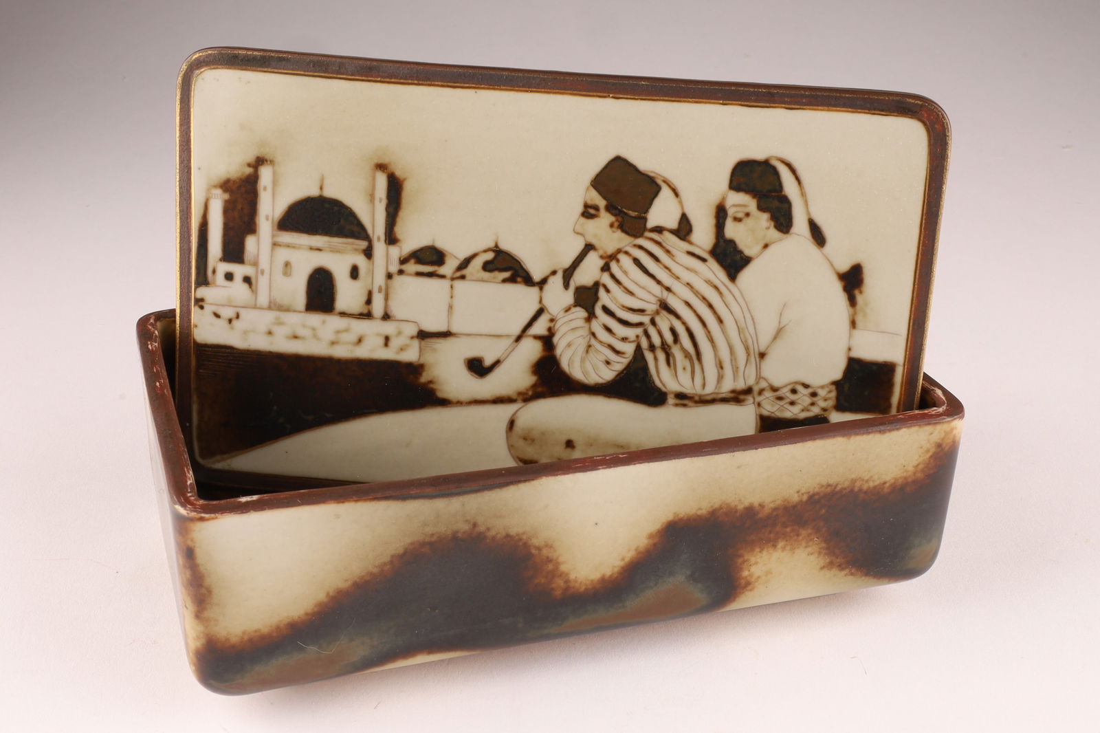 Gunnar Nylund Rorstrand Flambe Lidded Box, Stoneware with Hand-Etched Middle Eastern Scene c. 1930s: This rectangular box is a unique example from the Flambe collection, known for its experimental glazes and diverse forms. Gunnar Nylund served as the artistic director for Rorstrand, where this