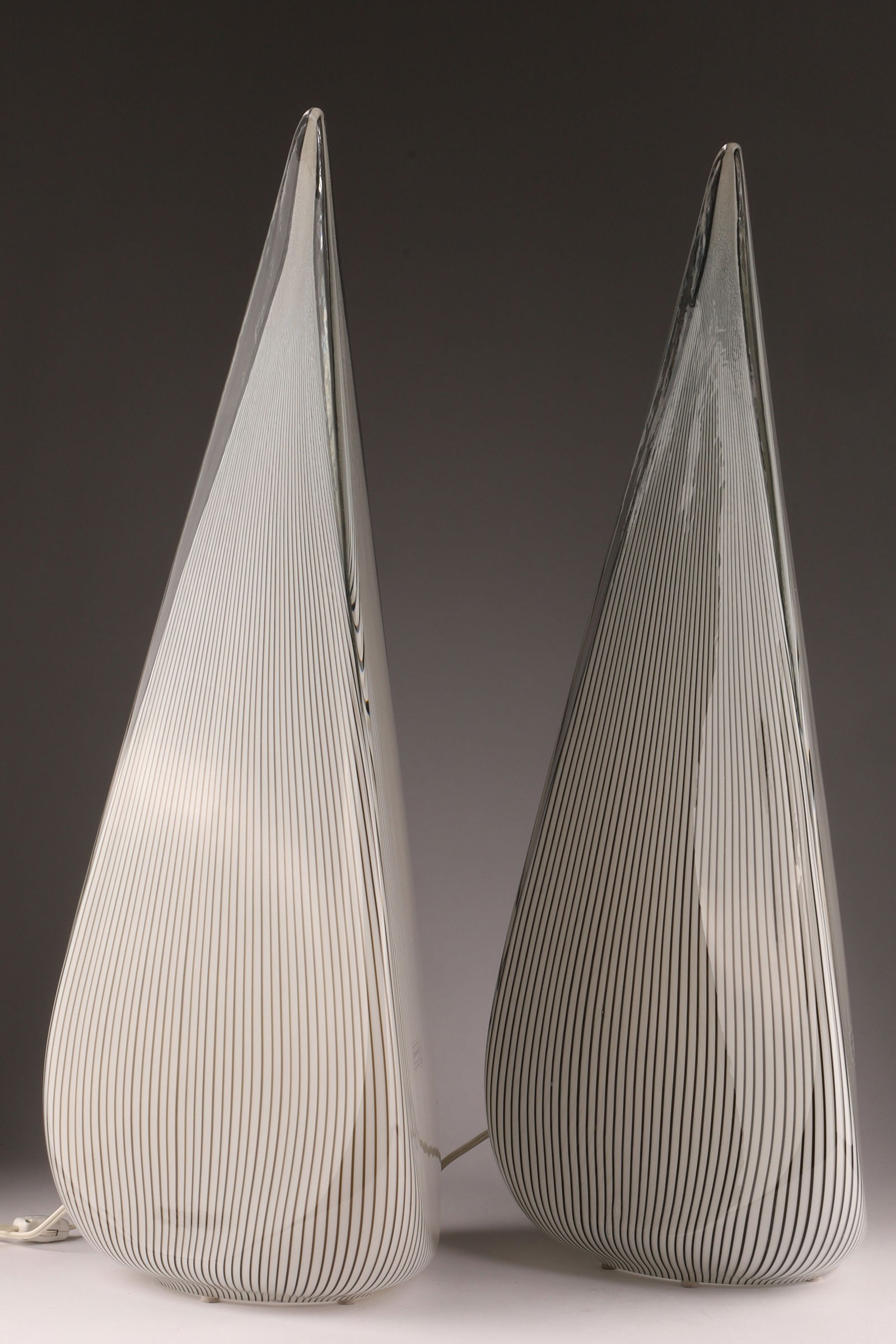 Pair of Effetre International Murano Glass Sculptural Lamps / Vases, c. 1980s-1990s: Pair of Signed Effetre International Murano Glass Lamps, c. 1980s Hand-blown sculptural glass bodies in clear and white filigrana (cane) design, elongated teardrop form on metal bases. Each signed E