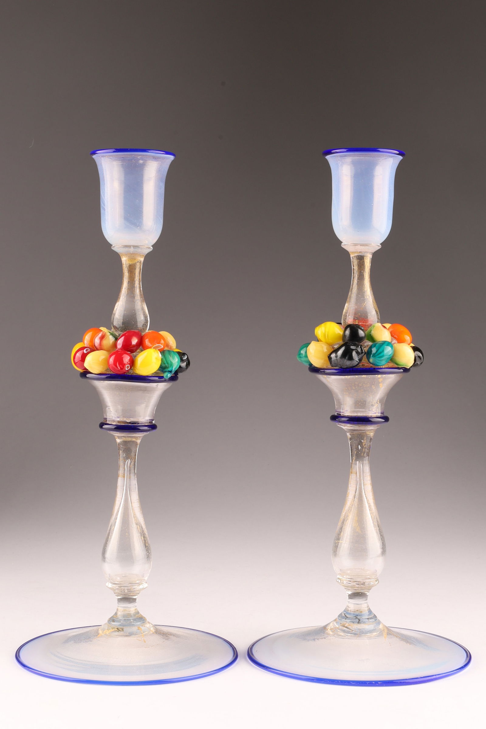 Attr. Salviati Venini Pair Iridescent Art Glass Candlesticks with Applied Fruit and Blue Rim: Attr. Salviati Venini Pair Iridescent Avventurina Art Glass Candlesticks with Applied Fruit on stem and Blue Rims, gold flecks within glass. 10 inches H x 4.5 W.