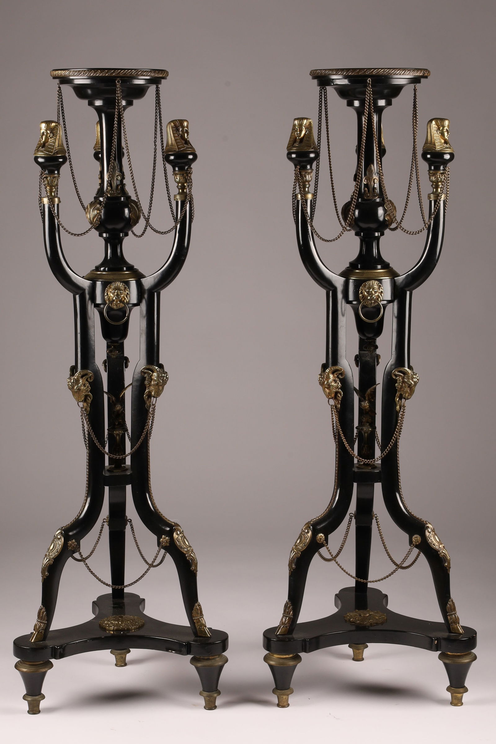 Pair of 20th C Egyptian Revival Gilt Bronze Ormolu Lacquered Pedestals: A pair of 20th-century Egyptian Revival pedestals made of gilt bronze and ormolu-mounted black lacquer. Standing 43.5" tall, each features a circular dished top. Three shaped legs, topped with E